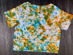 an orange, yellow and blue tie - dyed shirt sitting on top of a wooden floor