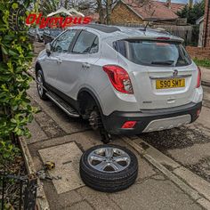 the car is parked on the side of the road with it's tire missing