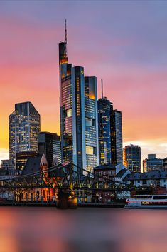 the city skyline is lit up at night, with skyscrapers in the background and boats on the water