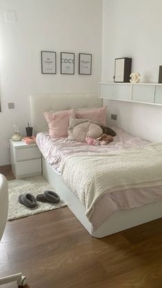 a bedroom with white walls and wood flooring has a pink bed spread on it