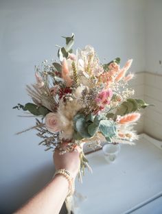 a bouquet of flowers is being held by a woman's hand in front of a window