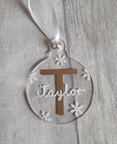 a glass ornament with the word taylor on it and snowflakes around it