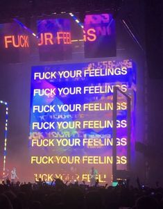 the stage is lit up with neon lights and words written on it as people watch