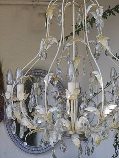 a white chandelier hanging from the ceiling in front of a mirror and wall