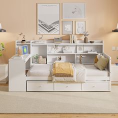 a white bed with drawers underneath it and pictures on the wall