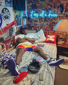 a man laying on top of a bed in a bedroom next to a wall covered with posters