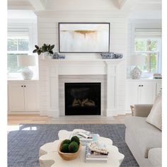 a living room with white walls and a fireplace in the center, surrounded by blue rugs