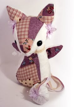 a stuffed animal is sitting on a white surface and wearing a purple dress with flowers