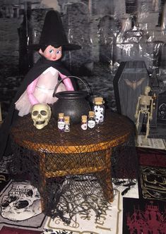 a doll sitting on top of a table next to some bottles and skull figurines