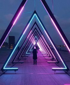 a person standing on a bridge that is lit up with purple and blue neon lights