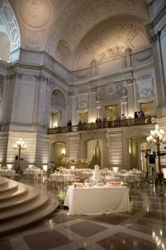 a banquet hall with tables and white linens set up for a formal function in the center