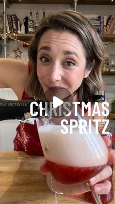 a woman holding a drink in front of her face with the words christmas spritz on it