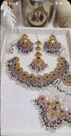 an elaborate necklace and earring set is displayed on a white tray next to other jewelry items