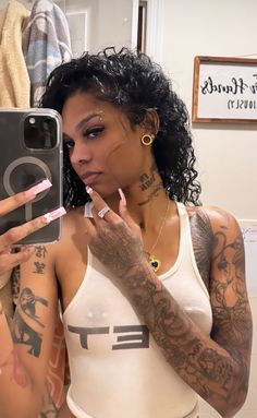 a woman taking a selfie in the mirror with her cell phone and tattoos on her arm