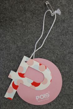 a pink and white polka dot letter hanging from a string on a gray carpeted floor