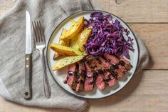 steak, coleslaw and potatoes on a plate next to a knife and fork