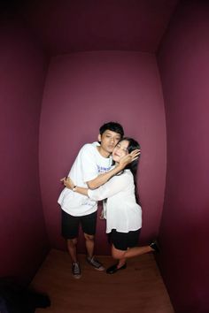 two people are hugging in a room with purple walls