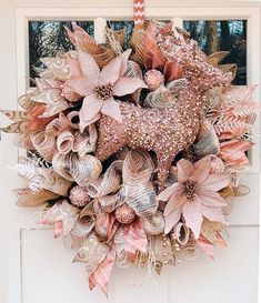 a wreath hanging on the front door of a house decorated with pink and gold flowers