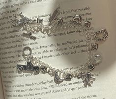 an open book with a silver charm bracelet on it