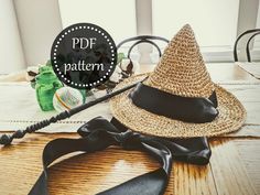 a straw hat sitting on top of a wooden table next to a black ribbon tie