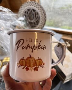 a hand holding a white coffee mug with hello pumpkin on the inside and brown lettering