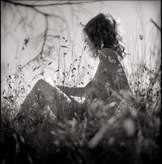 a woman sitting in the grass with her legs crossed