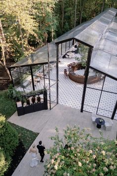 an aerial view of a couple walking through a garden area in front of a building