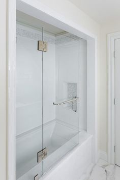 a bathroom with a glass shower door and marble floor