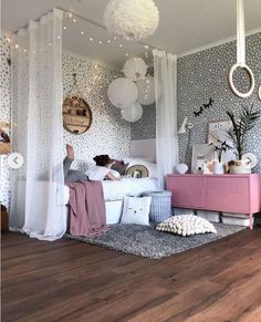 a person laying on a bed in a room with polka dot wallpaper and hanging lights