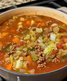 a pot filled with soup and vegetables on top of a stove burner next to an oven