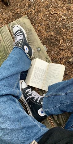 someone is sitting on a bench with their legs crossed and reading a book in front of them