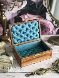 an open wooden box sitting on top of a table next to a mirror and key