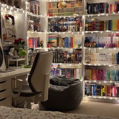 a room with many bookshelves filled with lots of books and lights on the walls