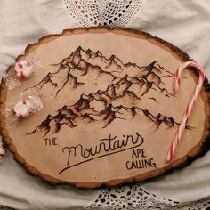 a wooden sign that says the mountains are calling with candy canes and peppermints