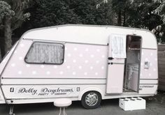 a pink and white polka dot trailer parked in front of a fenced off area