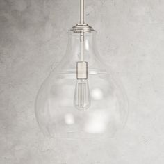 a clear glass light bulb hanging from a ceiling fixture on a concrete wall with no one around it