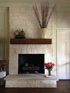 a living room with a fire place and flowers on the mantle