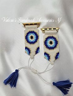 two blue and white beaded earrings with tassels hanging from the side on a white cloth