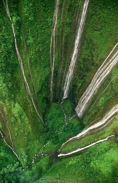 an aerial view of a waterfall in the middle of a green forest with water flowing down it