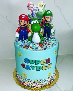 a blue cake with sprinkles and mario bros characters on it