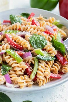 a white bowl filled with pasta salad on top of a table next to an apple