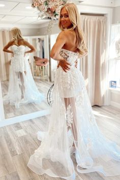 a woman in a wedding dress looking at herself in the mirror