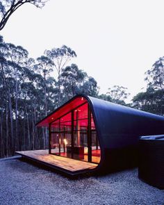 an unusual house in the woods is lit up with red lights and surrounded by trees