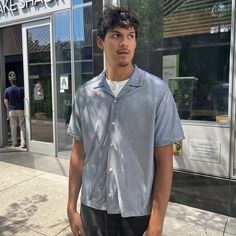 a man standing on the sidewalk in front of a fake snake snack store with his hands in his pockets