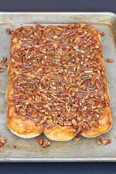 a square pastry with pecans on top is sitting on a baking sheet, ready to go into the oven