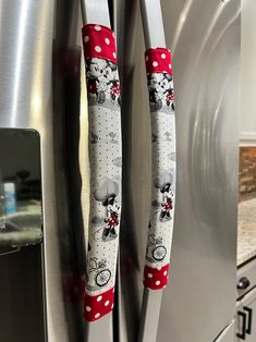 two mickey mouse kitchen utensils hanging from the side of a stainless steel refrigerator