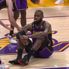 a basketball player sitting on the floor with his foot up