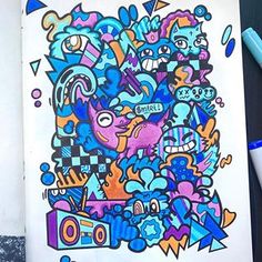 an open notebook with colorful doodles on the cover and some markers next to it