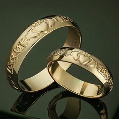 two gold wedding rings sitting on top of each other