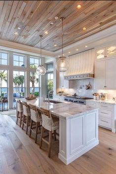 a large kitchen with white cabinets and wooden floors, along with an island in the middle